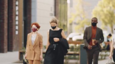 Covid-19 salgını sırasında şehirde sokakta yürüyen koruyucu maskeli çok ırklı iş adamları