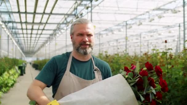 Skäggig Medelålders Man Förkläde Bär Bukett Röda Rosor Genom Blommans — Stockvideo