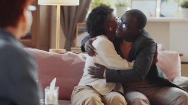 Afrika kökenli Amerikalı çift, aile terapisi seansında birbirlerine sarılıyor ve psikologla konuşuyor.