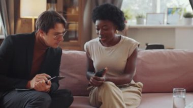 Genç Afrikalı Amerikalı kadın, terapi seansı sırasında akıllı telefon ekranında beyaz psikologla bir şey tartışıyor.