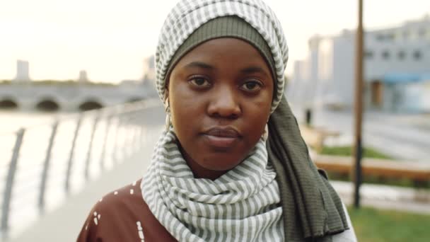 年轻的黑人穆斯林妇女头戴头巾 看着相机 白天站在室外的肩部Pov — 图库视频影像