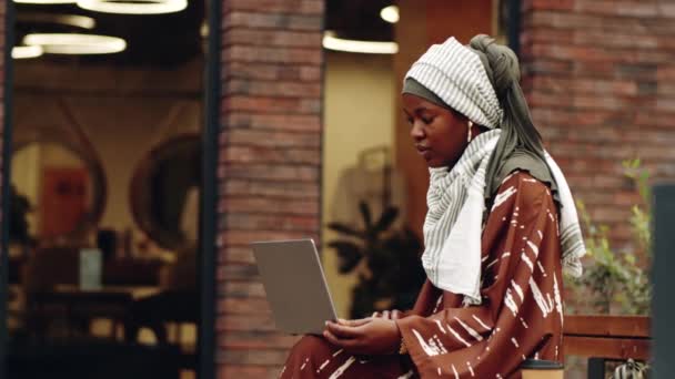 Mediano Largo Joven Feliz Mujer Negra Usando Hijab Sentado Banco — Vídeos de Stock