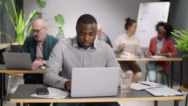 Młody Afroamerykanin Piszący Laptopie Pijący Wodę Szkła Przy Biurku Podczas — Wideo stockowe