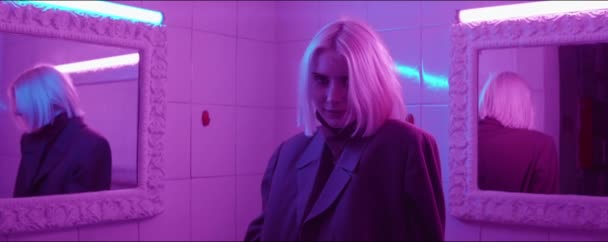 Young attractive woman standing between two mirrors in room with purple neon light and posing for camera — Stock Footage Young Attractive Woman Standing Two Mirrors Room Purple Neon Light — Stock Video