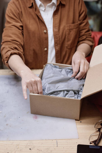 Женщина упаковывает посылку для доставки