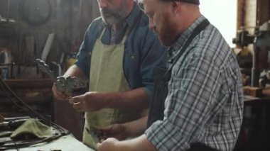Demircide birlikte çalışırken iki profesyonel demirci dekoratif demir detaylarını tartışıyor.