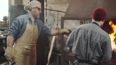 Demirci, demir çubuğu ateşten çıkardı ve demir ocağında çalışırken örse vurduğu için kıdemli meslektaşına verdi.