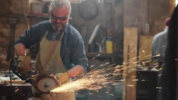 エプロンの白髪鍛冶屋 鍛冶屋で仕事で切削ホイールを使用して保護手袋やゴーグル — ストック動画