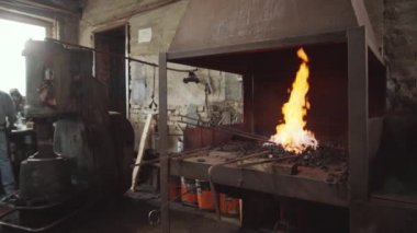 Demirhanede yanan ateşin görüntüsünü yakınlaştırın. Demirci atölyesinde demir çubuklar alevler içinde ısıtılıyor.