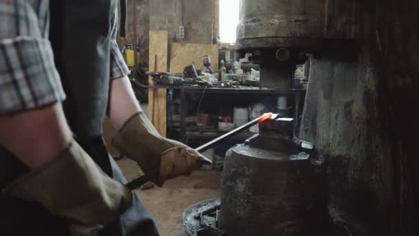 鍛冶屋で働く力ハンマーで加熱された金属棒を鍛造保護手袋の鍛冶屋のミッドセクションショット — ストック動画