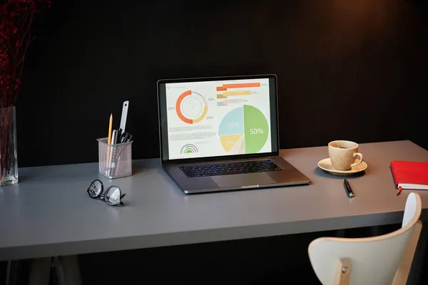 Laptop med diagram på bordet — Stockfoto