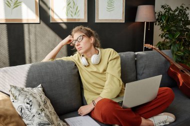 Odada dizüstü bilgisayarlı bir kadın oturuyor.