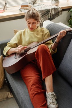Kanepede gitar çalan kadın.