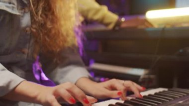 Sentezleyici çalan ve iş arkadaşıyla birlikte ses prodüksiyonunda şarkı söyleyen kadını yakın çekim yapın.