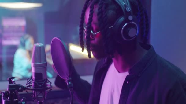 보라색 네온등을 녹음실에서 마이크로폰으로 노래를 부르고 아프리카 미국인 — 비디오