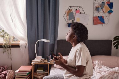 Telefonu olan kadın evde oturuyor.