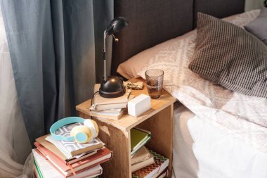Çalar saati ve kitapları olan bir yatak masası.
