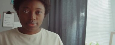 Genç ve güzel Afro-Amerikan bir kadının göğüs portresi. Sabah evde kameraya poz veriyor.