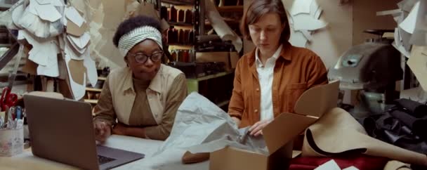 Белая Женщина Упаковывает Обувь Коробку Время Афроамериканская Коллега Использует Ноутбук — стоковое видео