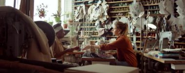 Genç Afrikalı Amerikalı ve beyaz kadınlar ayakkabı imalathanesinde çalışırken ayakkabı modellerini tartışıyorlar.