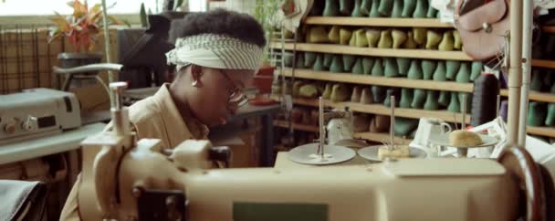 年轻的非洲裔美国妇女在制鞋车间的桌子边工作时用剪刀切割皮革的弧形照片 — 图库视频影像
