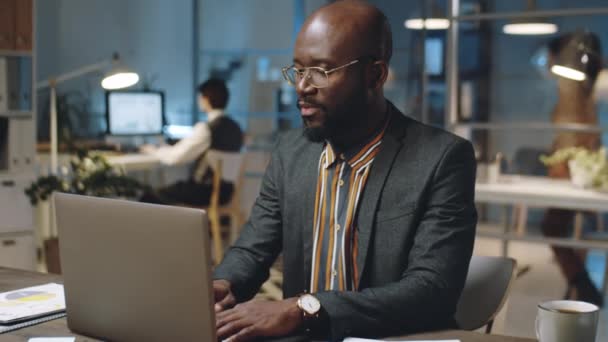 Afroamerikanischer Geschäftsmann Mit Brille Und Formalem Outfit Arbeitet Abends Schreibtisch — Stockvideo