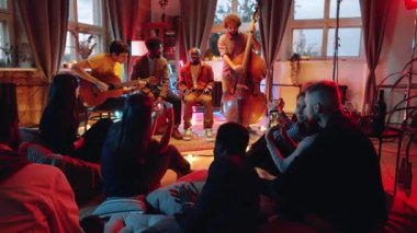 Çoklu etnik çeşitlilikte müzik enstrümanları çalan ve stüdyodaki küçük konserlerdeki insanlar için şarkı söyleyen müzik grubunu yakınlaştırın.