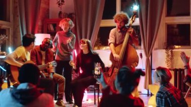 Genç çok ırklı kadınlar ve erkek konserde insanlar için şarkı söylerken gitar ve çift bas müzik eşlik ediyor.