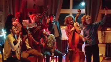 Bir grup neşeli genç, gülümseyen ve müzik bandıyla kameraya poz verirken konserden sonra birlikte fotoğraf çekiyorlar.