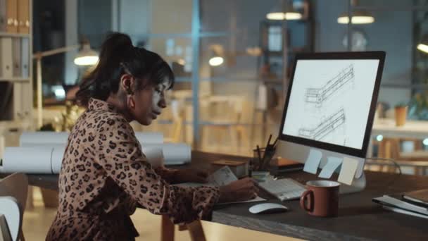 Mujer Hispana Examinando Plan Arquitectónico Computadora Tomando Notas Papel Mientras — Vídeo de stock