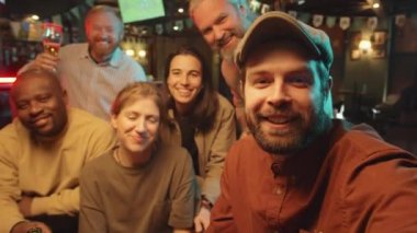 Bir grup kadın ve erkek barda harika bir akşam geçiriyorlar. Akıllı telefon kamerasıyla selfie çekiyorlar.