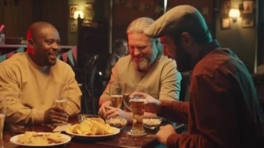 Dört yakışıklı adam modern barda birlikte oturup bira içip, abur cubur yiyip sohbet ediyorlar.