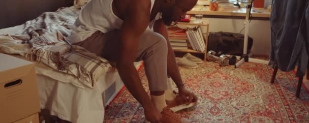 Strzał Afroamerykanina Zakładającego Buty Bluzę Sypialni Domu — Wideo stockowe