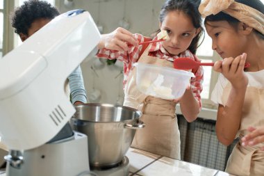 Çocuklar takımda pasta için krema yapıyor.