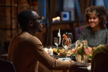 Adam arkadaşlarıyla yemek masasında oturuyor.