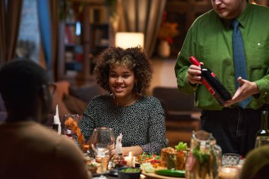 Arkadaşlarıyla yemek masasında oturan bir kadın.