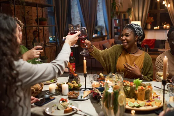 Arkadaşlar masada kırmızı şarapla kadeh kaldırıyor.