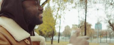 İki neşeli Afro-Amerikan erkeğin PAN 'ı sonbahar günü parkta buluşur, birbirlerini selamlar, gülümser ve konuşurlar.