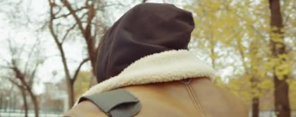 胸を撃たれたアフリカ系アメリカ人男性秋の日にリュックを持って公園を歩く — ストック動画