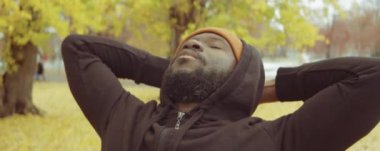 Afro-Amerikan bir adamın spor giyim kuşamında, sonbahar günü parkta antrenmandan önce ısınma egzersizleri yaparken göğsünü dik tut.