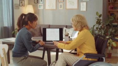 Genç bir kadının gönüllü olarak gönüllü olarak yaşlı bir kadına bir şeyler öğretirken çekilmiş yatay bir fotoğrafı.