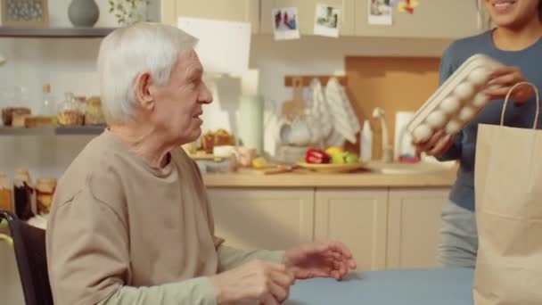 Özürlü Yaşlı Adam Için Çantalardan Yiyecek Alıp Götüren Neşeli Genç — Stok video
