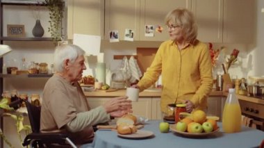 Kıdemli kadın sabah vaktini kocasıyla mutfakta ona kahve hazırlayıp sohbet ederek geçiriyor.