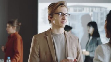 Genç yakışıklı adam plastik bardak tutuyor ve iş için bayan meslektaşıyla konuşuyor.