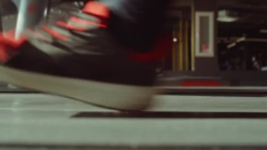 Beden eğitiminde koşu bandında yürüyen tanınmayan bir adamın yan görüntüsü.