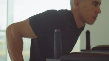 Spor kıyafetleriyle spor salonunda paralel bar dalışı yapan atletik adamı yukarı kaldır.
