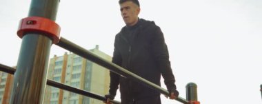 Paralel barlarda spor yaparken atletizm antrenmanının düşük açılı çekimi.