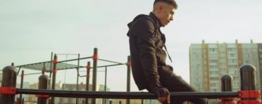 Sporcunun oyun parkında antrenman yaparken paralel barlarda planche çizerken ki arkası.