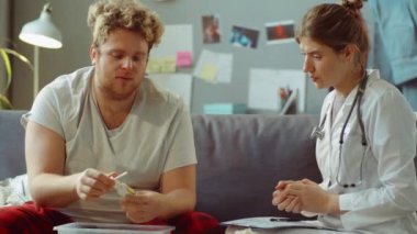 Kanepede oturan ve hasta bir hastayla boğaz spreylerini tartışan kadın doktor.