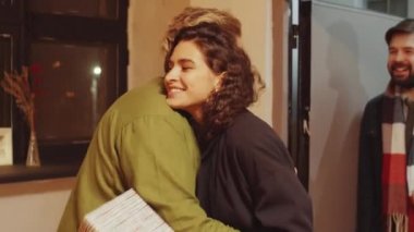 En iyi arkadaşlarını karşılayan genç çiftin yatay orta pozu.